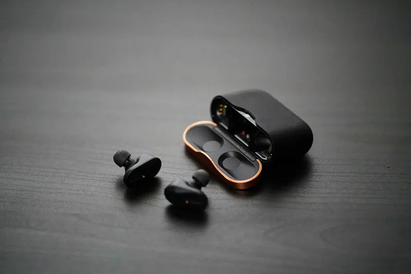 Black wireless earbuds resting beside their charging case