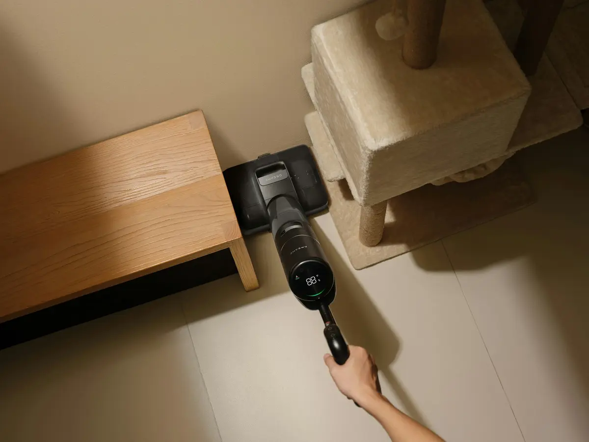Person vacuuming a corner with a cordless vacuum
