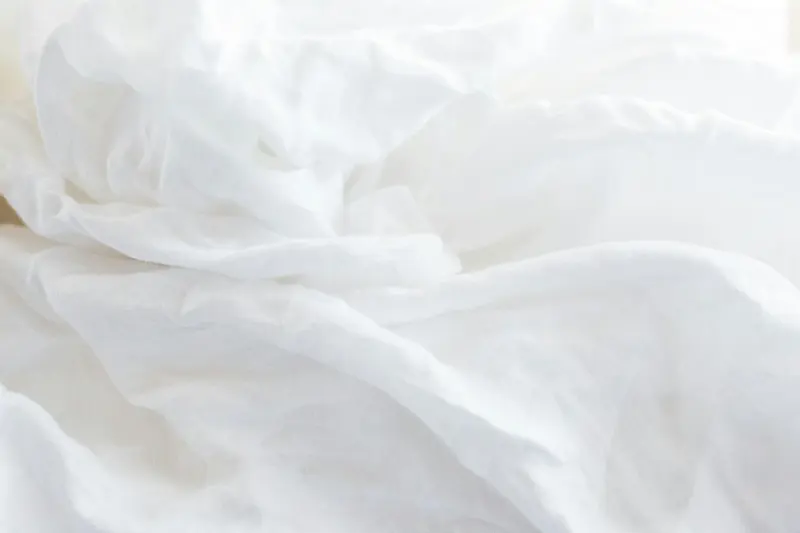 A bed dressed in white sheets and pillows
