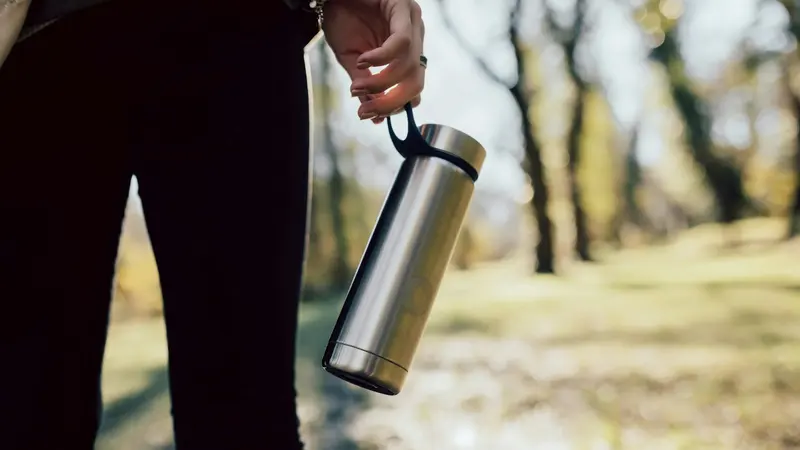 A person holding a stainless steel vacuum flask